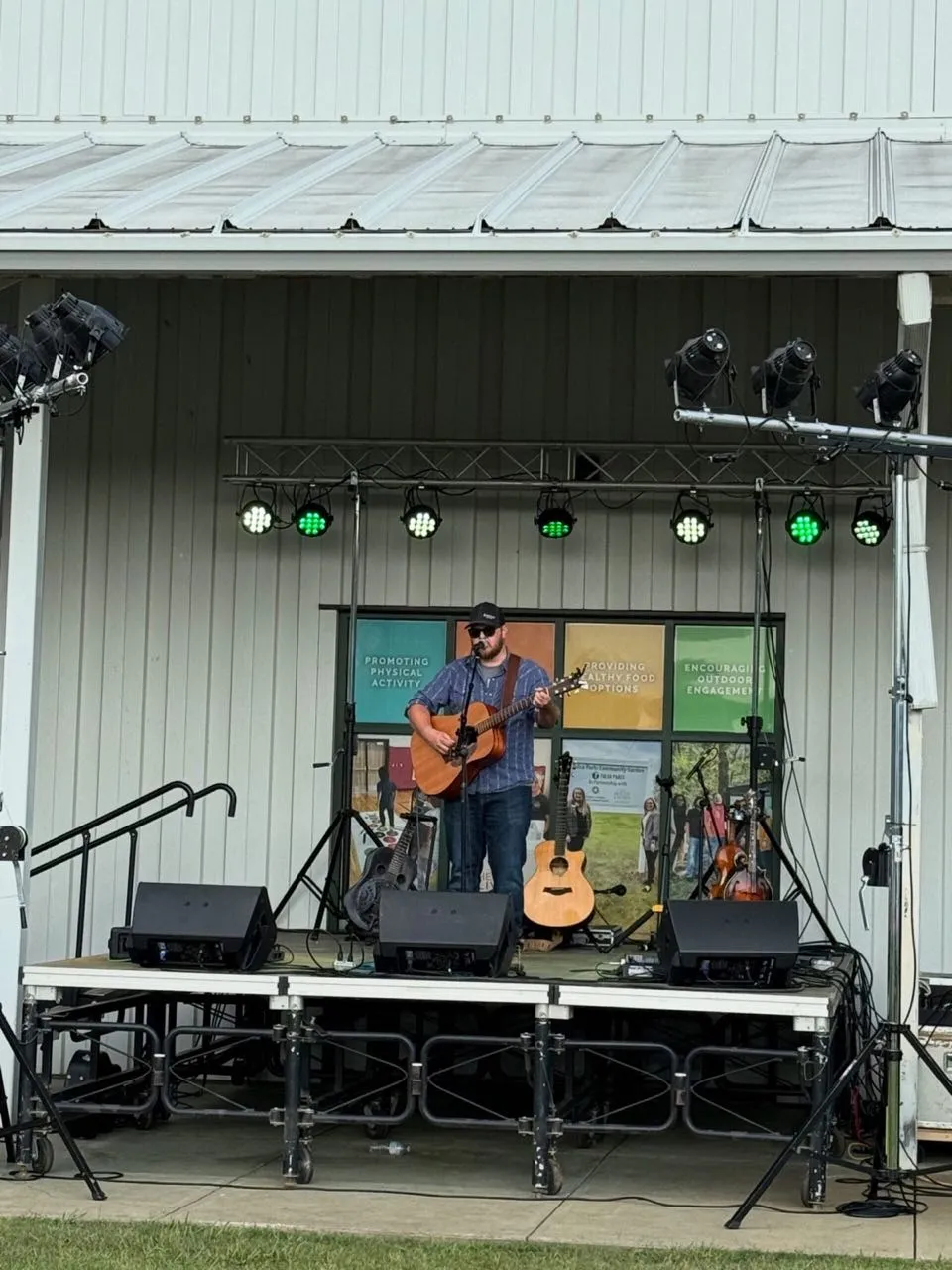 Acoustic performer on a portable stage with par can lighting provided by Phase 3 Live at a community event