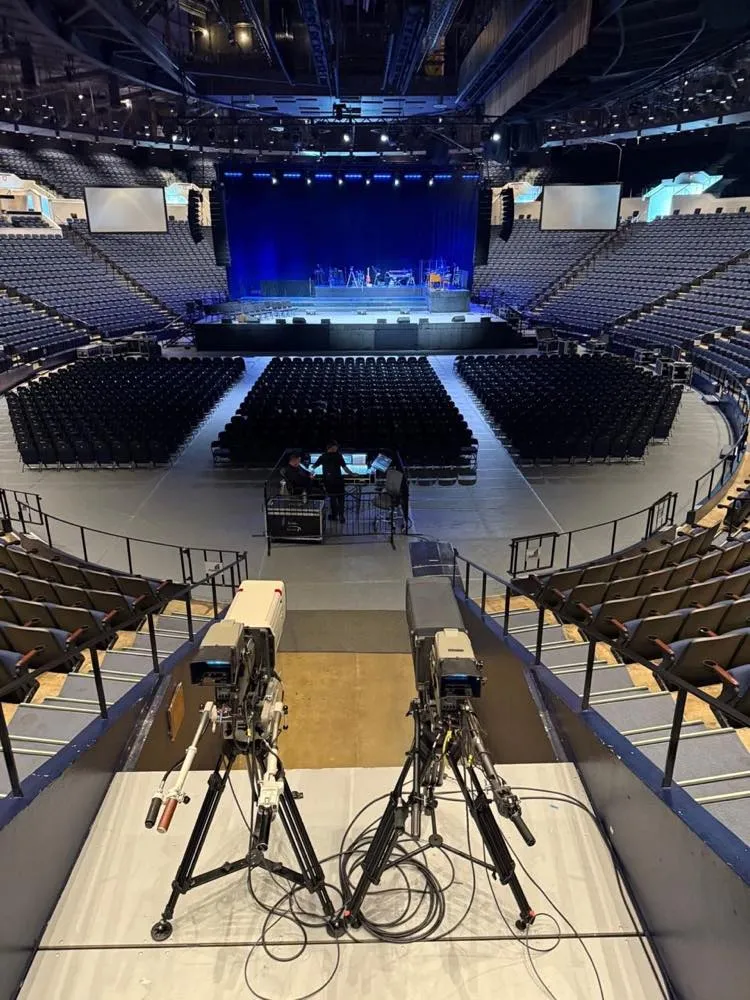 Broadcast cameras and front-of-house position overlooking a concert stage built by Phase 3 Live in an arena