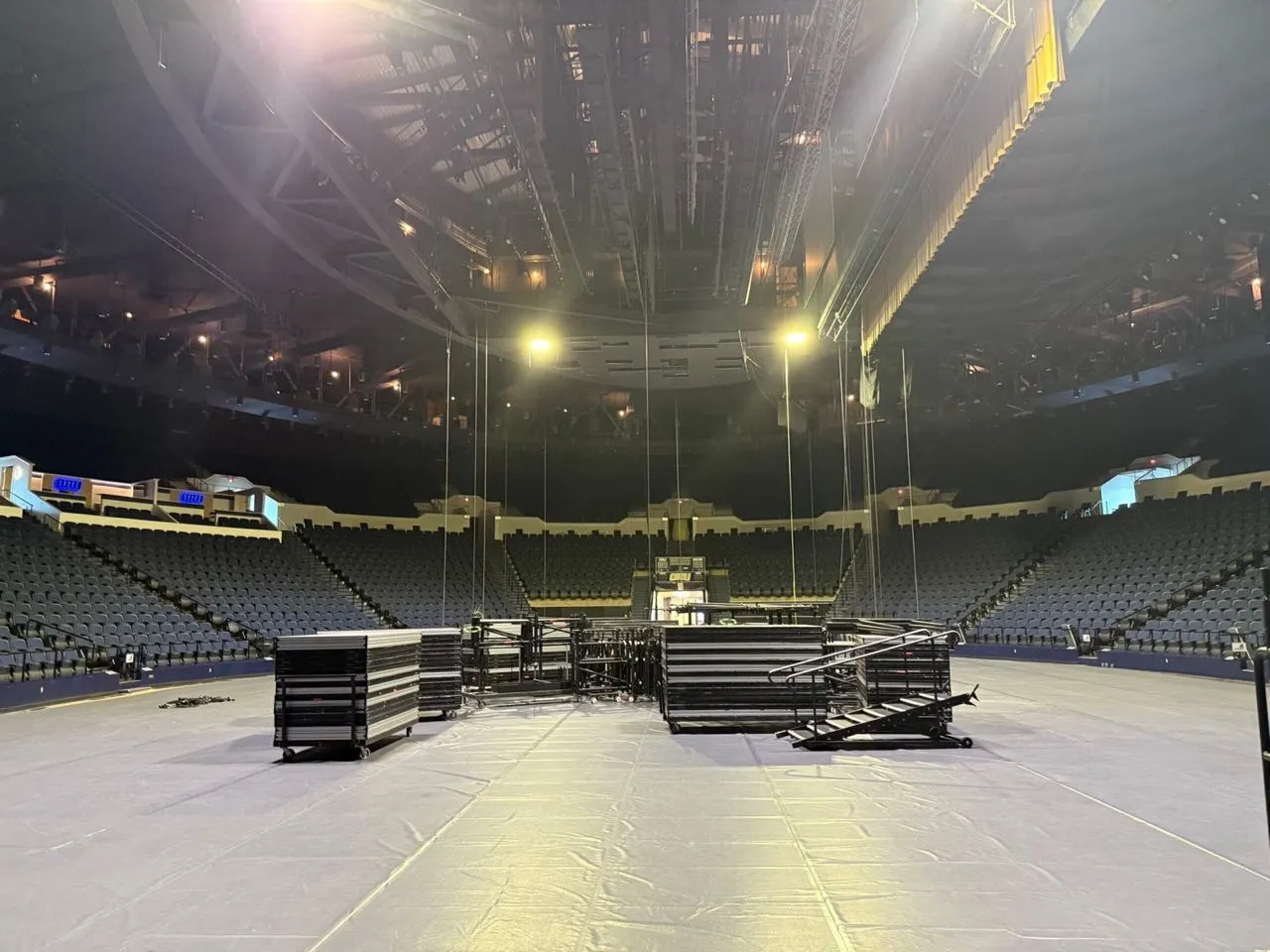Arena floor during a stage build with risers and rigging staged by Phase 3 Live