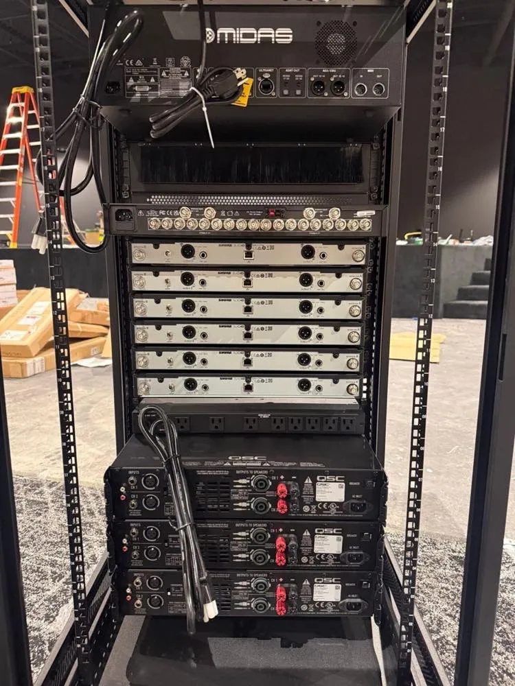 Audio equipment rack with Midas, Shure wireless, and QSC amplifiers assembled by Phase 3 Live during a venue installation.