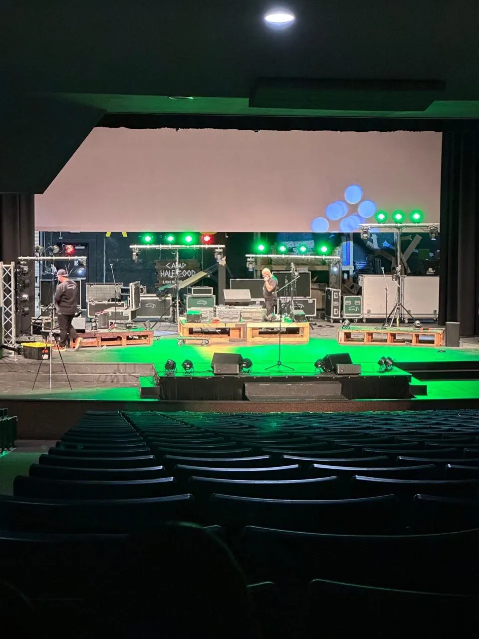Phase 3 Live crew setting stage lighting and equipment for a themed event in an auditorium