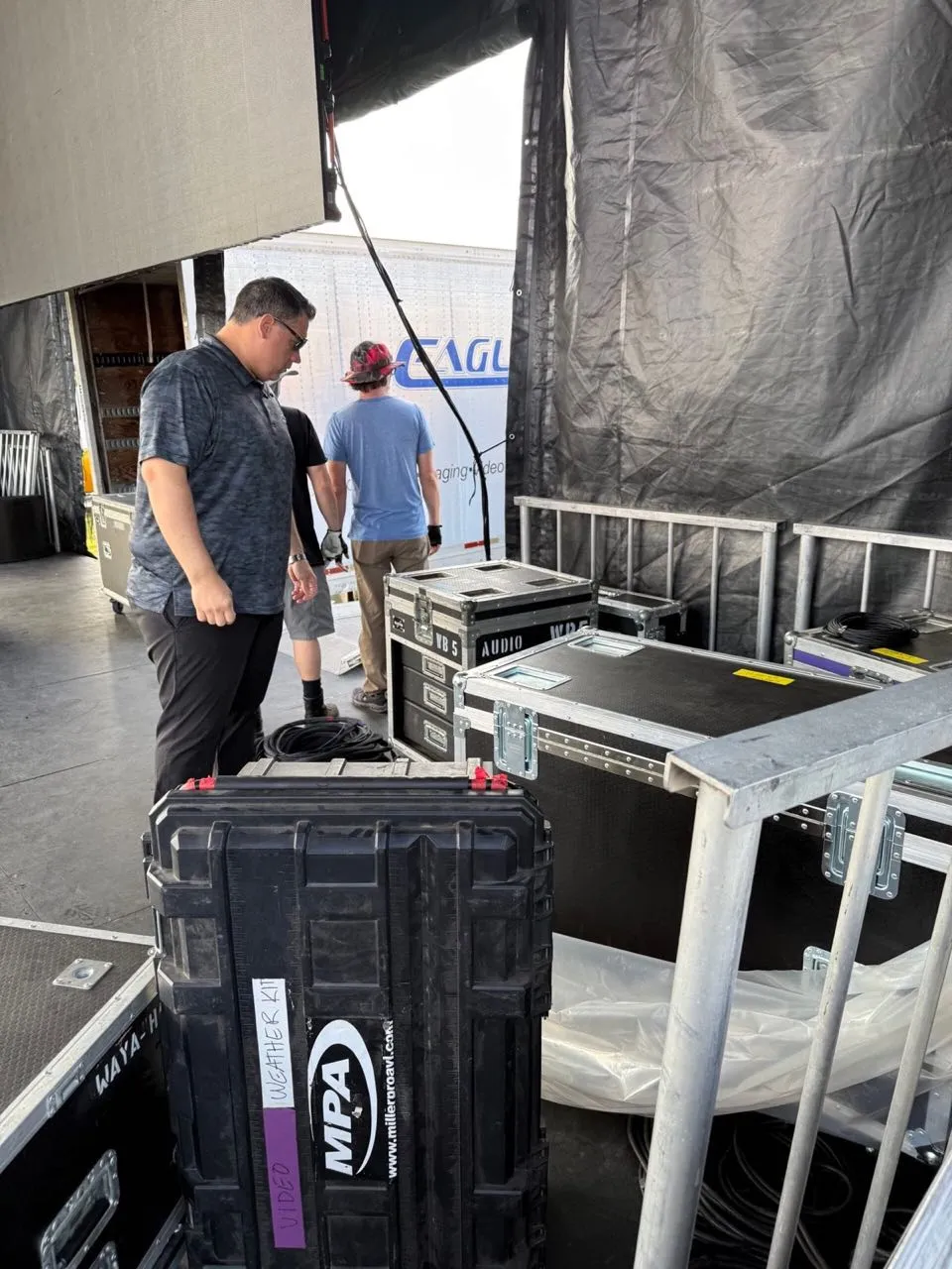 Phase 3 Live crew loading audio and video road cases backstage at an outdoor event