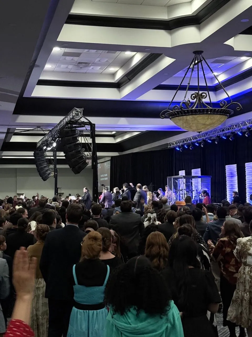 Crowd gathered in a hotel ballroom during a conference service with truss-mounted sound and lighting by Phase 3 Live