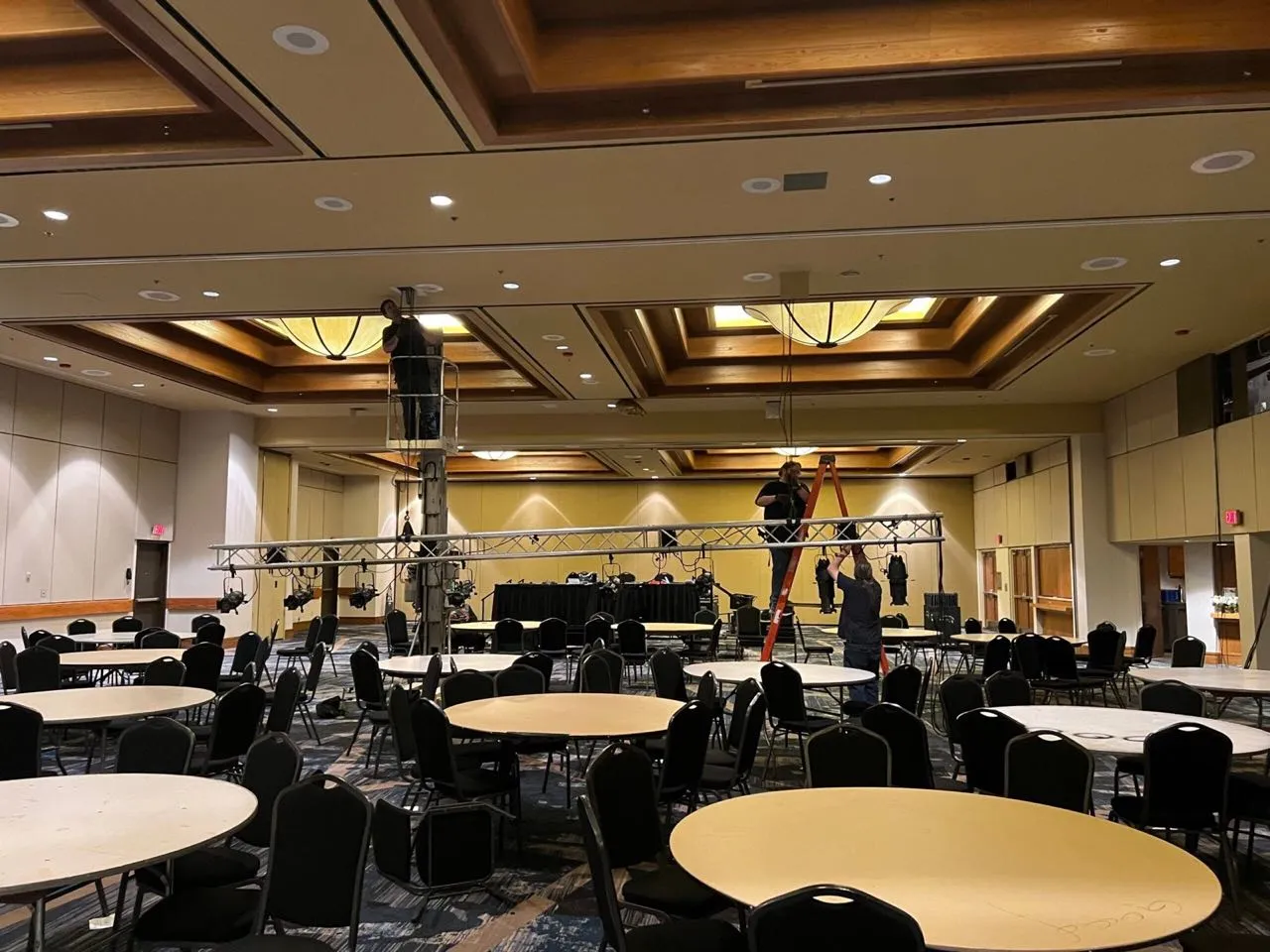 Crew assembling a lighting truss over banquet tables for a corporate event produced by Phase 3 Live