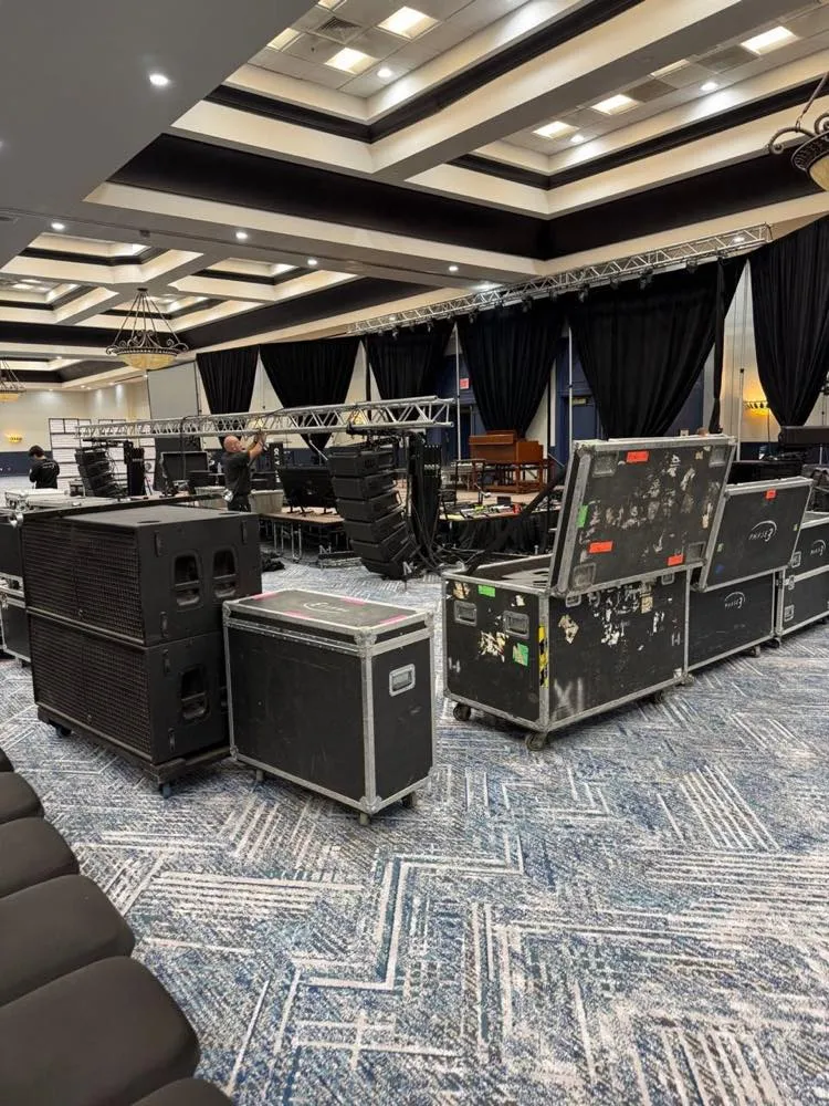 Road cases and speaker stacks during a Phase 3 Live load-in for a ballroom event production.