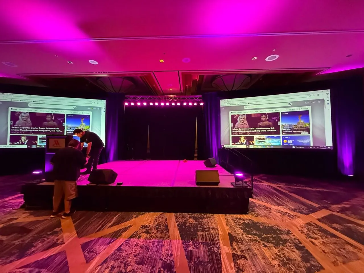 Magenta-lit ballroom stage with truss lighting and dual screens produced by Phase 3 Live