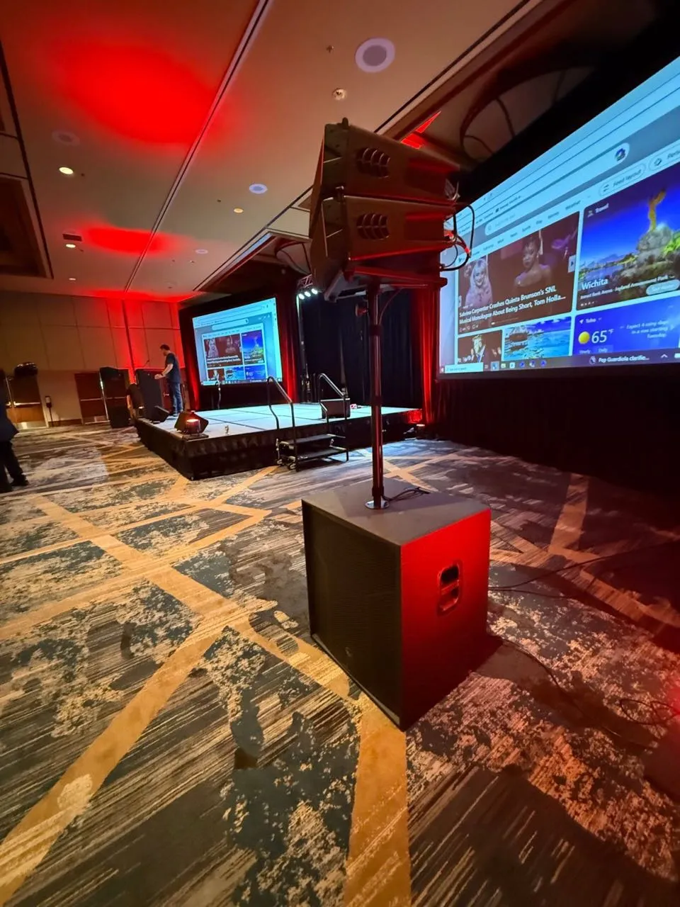 Corporate ballroom stage with red uplighting, projection screens, and PA set by Phase 3 Live