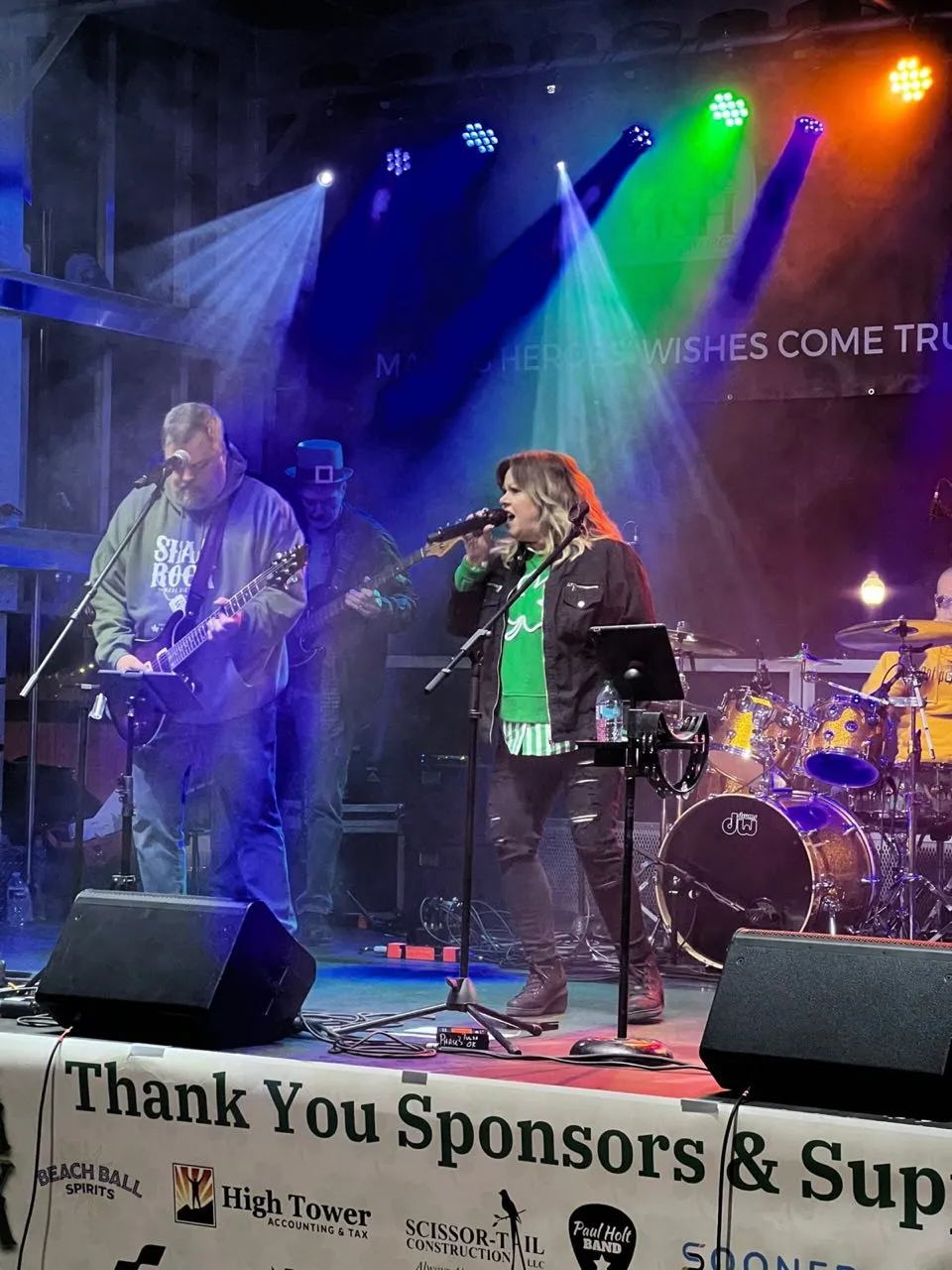 Band performing under colorful stage lighting at a charity concert produced by Phase 3 Live