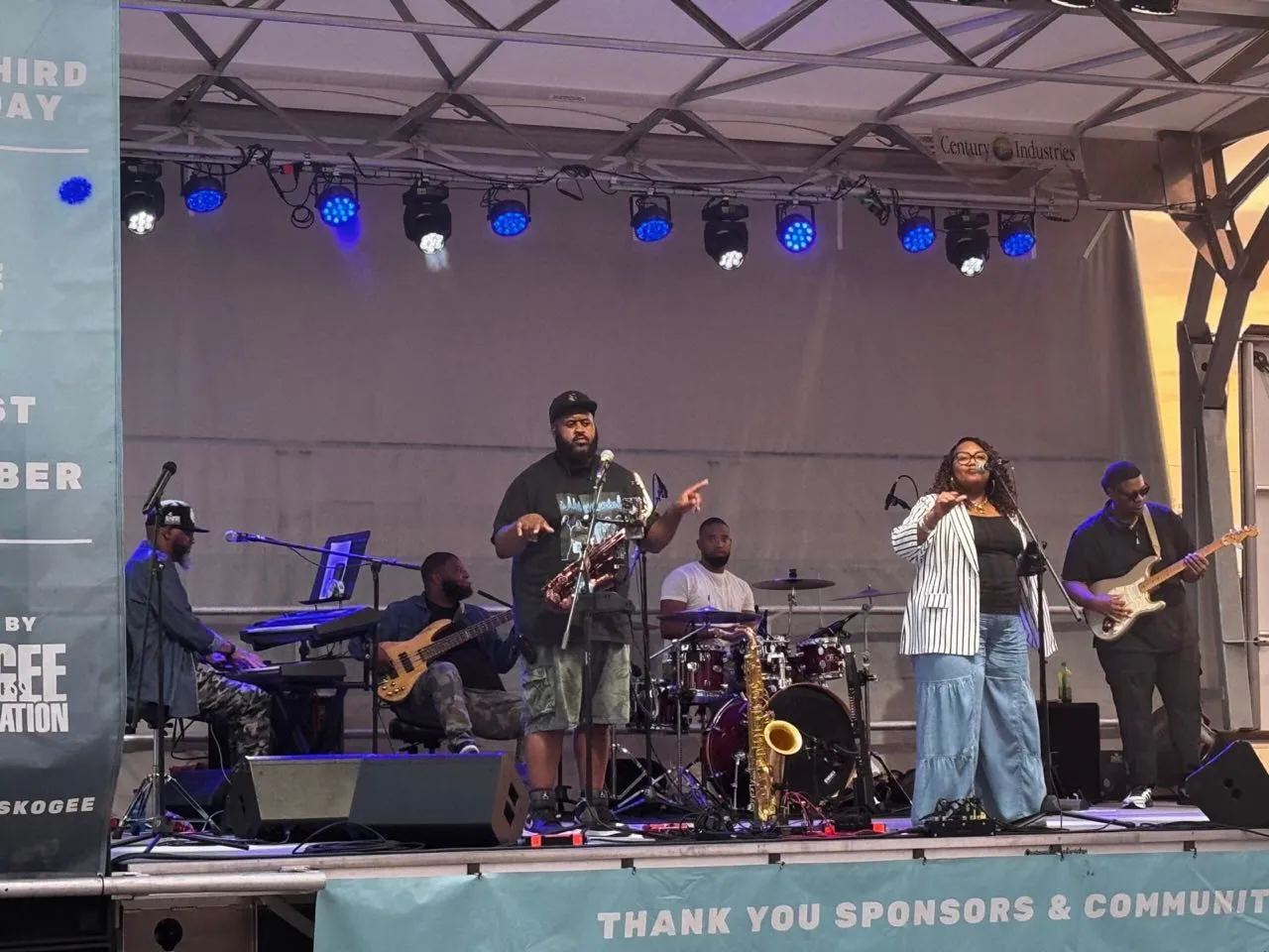 Band performing under blue stage lighting on a mobile stage produced by Phase 3 Live