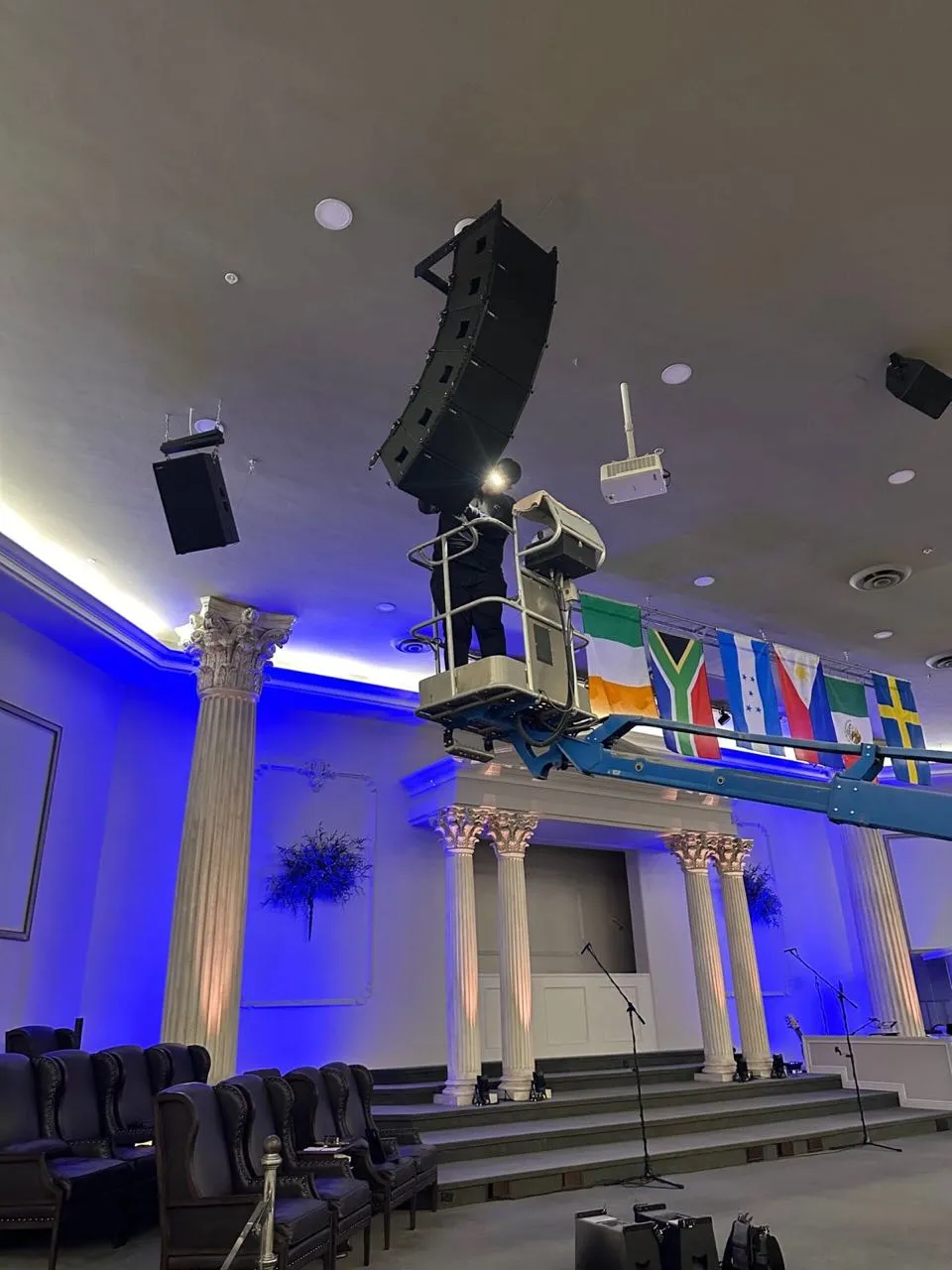 Phase 3 Live technician on a boom lift rigging a line array inside a church sanctuary