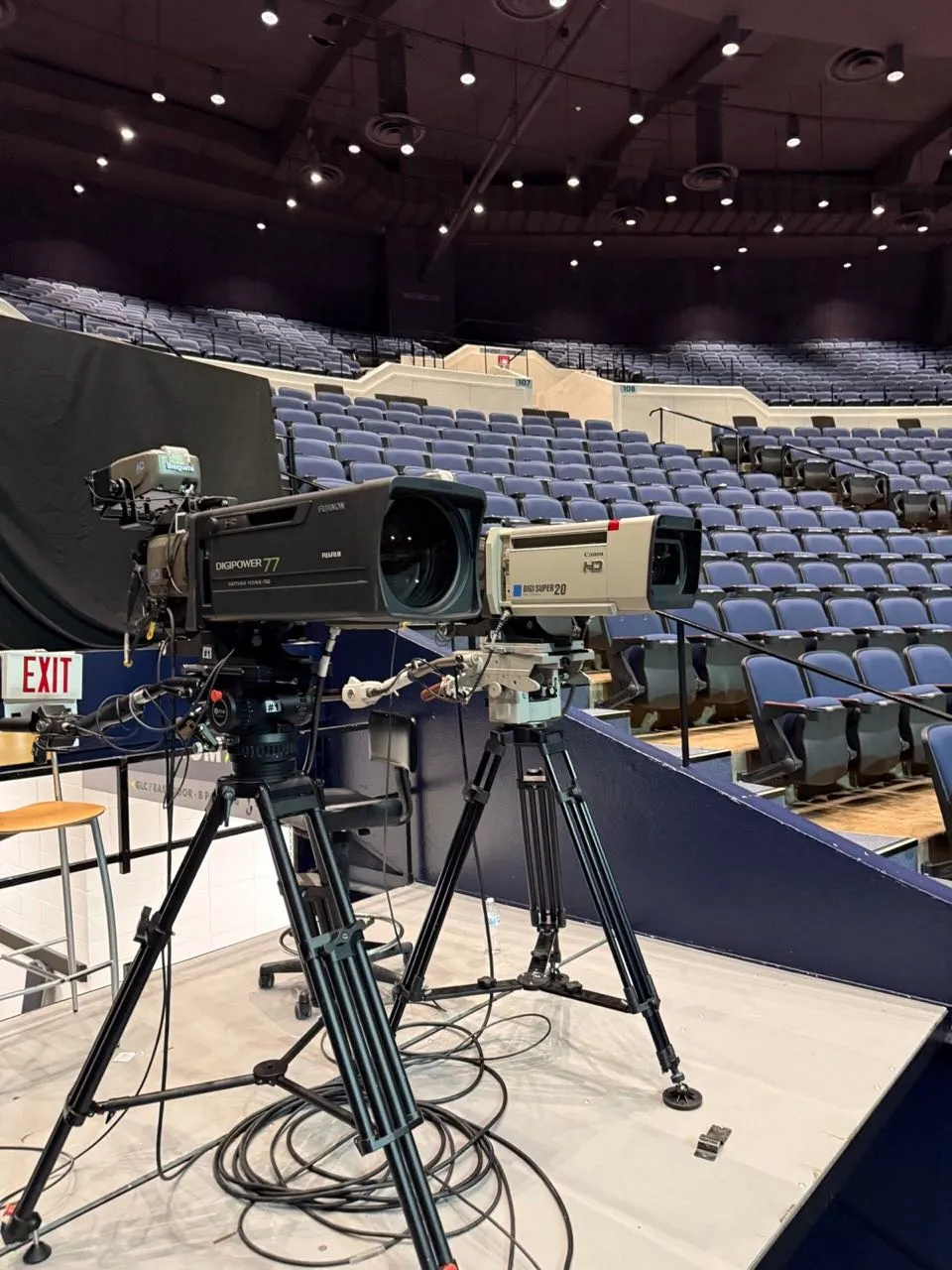 Broadcast cameras staged on a platform in an empty arena before an event