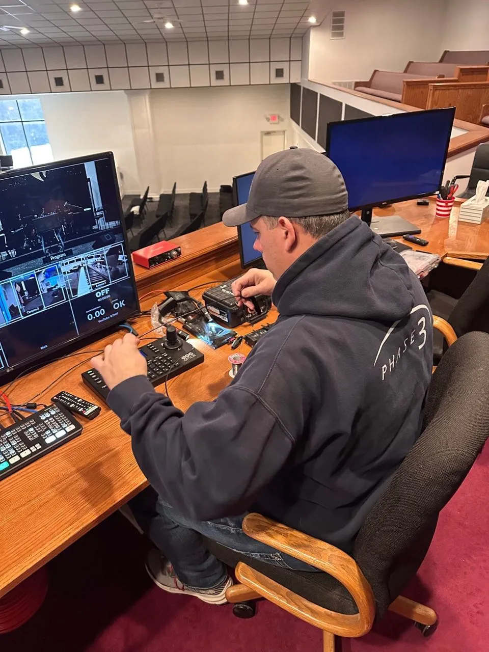 Phase 3 Live operator controlling live event cameras from a video station overlooking an auditorium