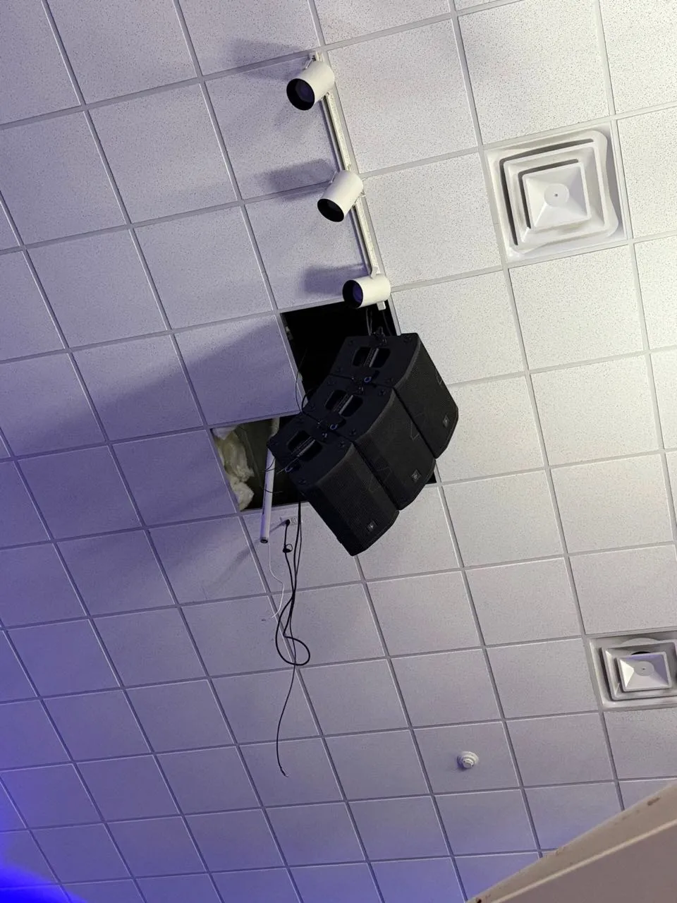 Compact line array speakers being mounted through a drop ceiling during an AV installation by Phase 3 Live