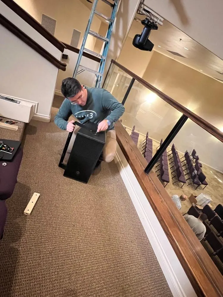 Phase 3 Live technician installing a balcony loudspeaker in a church sanctuary