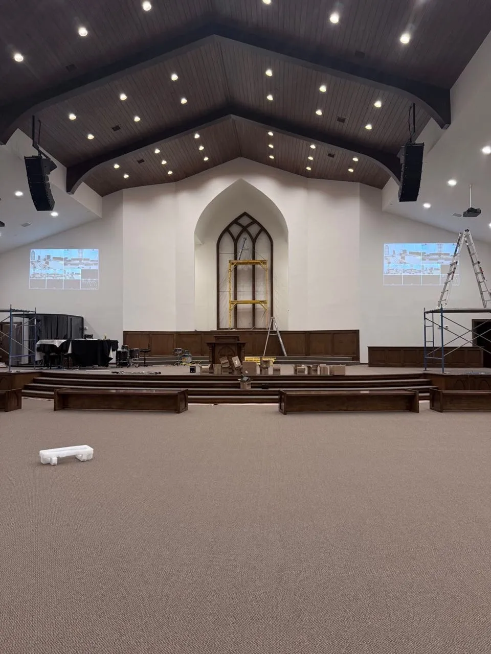Line-array speakers and projection installed by Phase 3 Live in a church sanctuary with a vaulted wood ceiling.