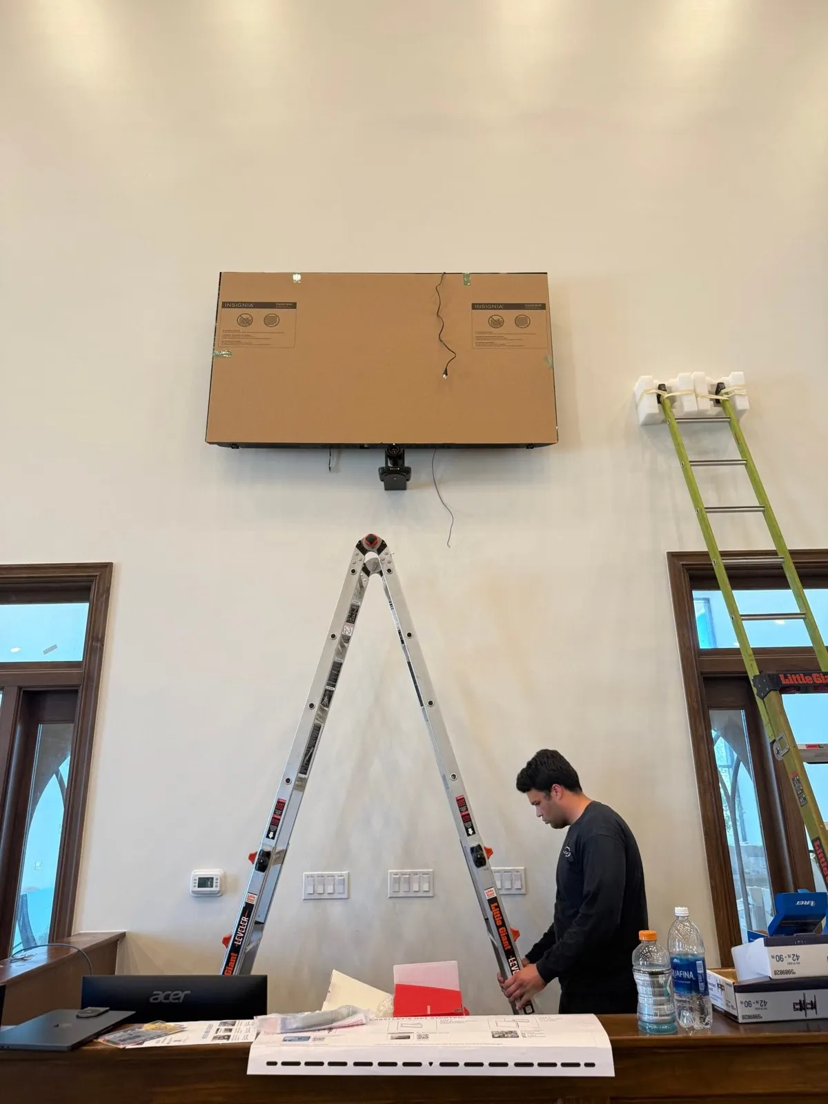 Phase 3 Live technician installing a wall-mounted display and PTZ camera in a church sanctuary.