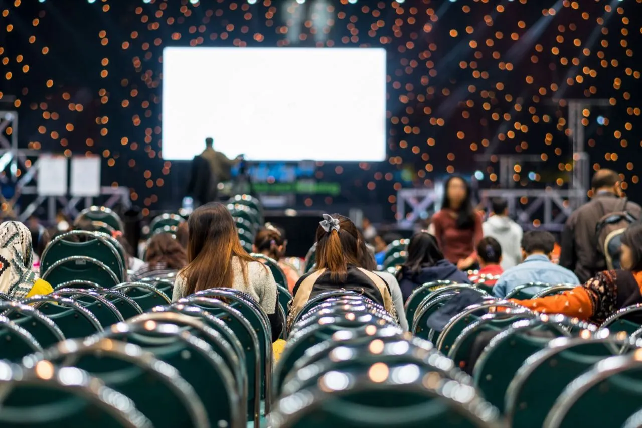 Audience watching a presentation on a large screen at a conference event