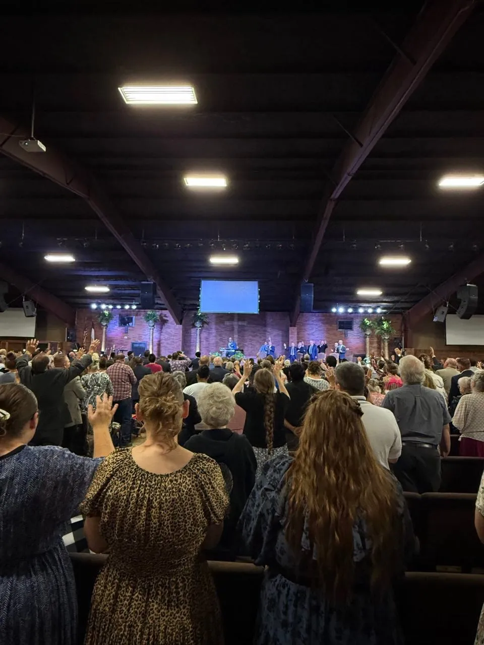 Congregation standing with raised hands during a church worship service with sound and lighting support