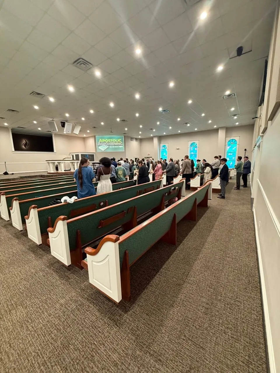 Congregation standing in worship at a church service with screens and sound support from Phase 3 Live