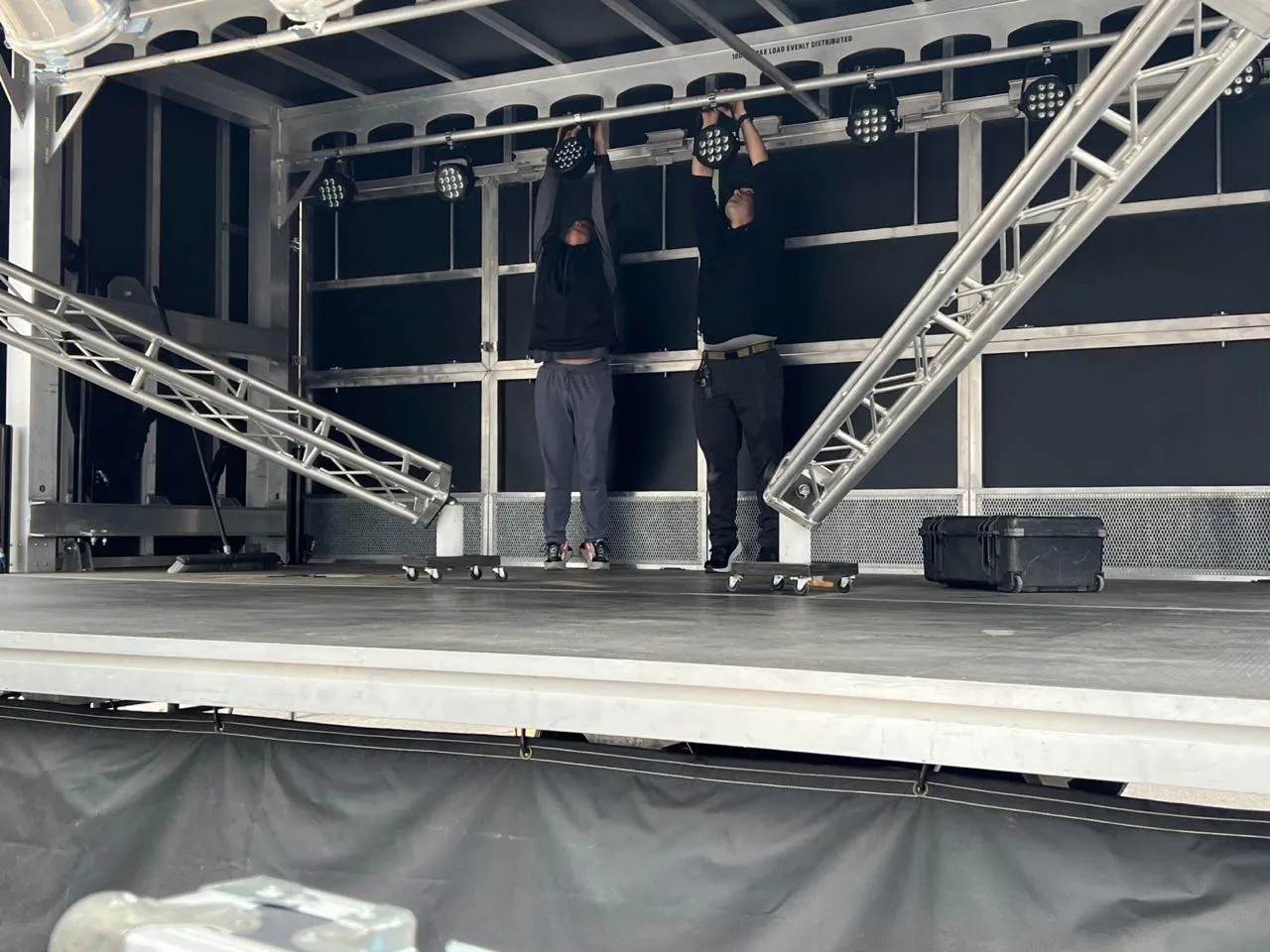 Phase 3 Live crew hanging LED stage lights on truss during a mobile stage build