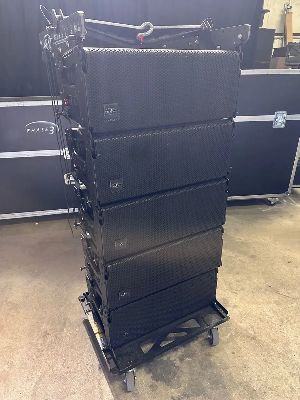 DAS line array modules on a transport cart beside a Phase 3 Live road case in the shop
