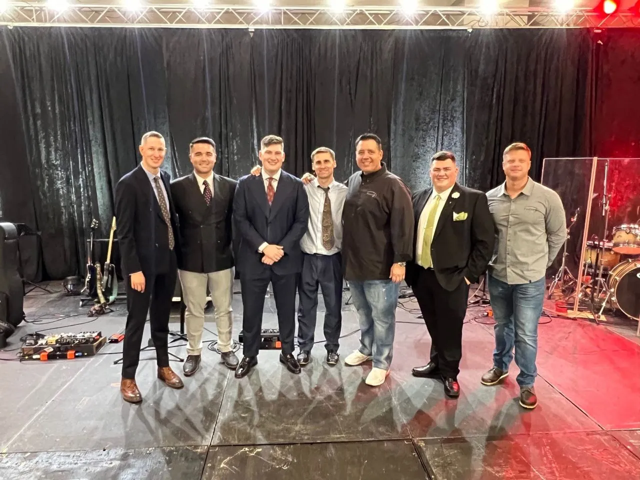 Performers and event hosts posing on a stage produced by Phase 3 Live after an evening event.