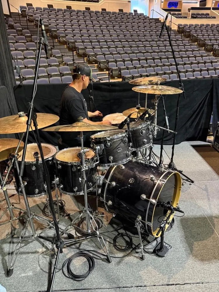 Drummer at a fully miked kit during arena soundcheck for a Phase 3 Live production