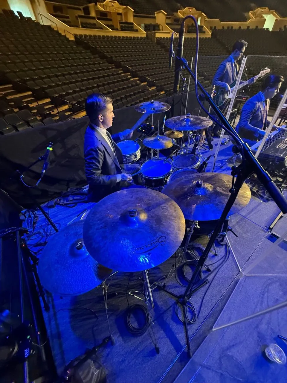 Drummer performing under blue stage lighting at an arena event produced by Phase 3 Live