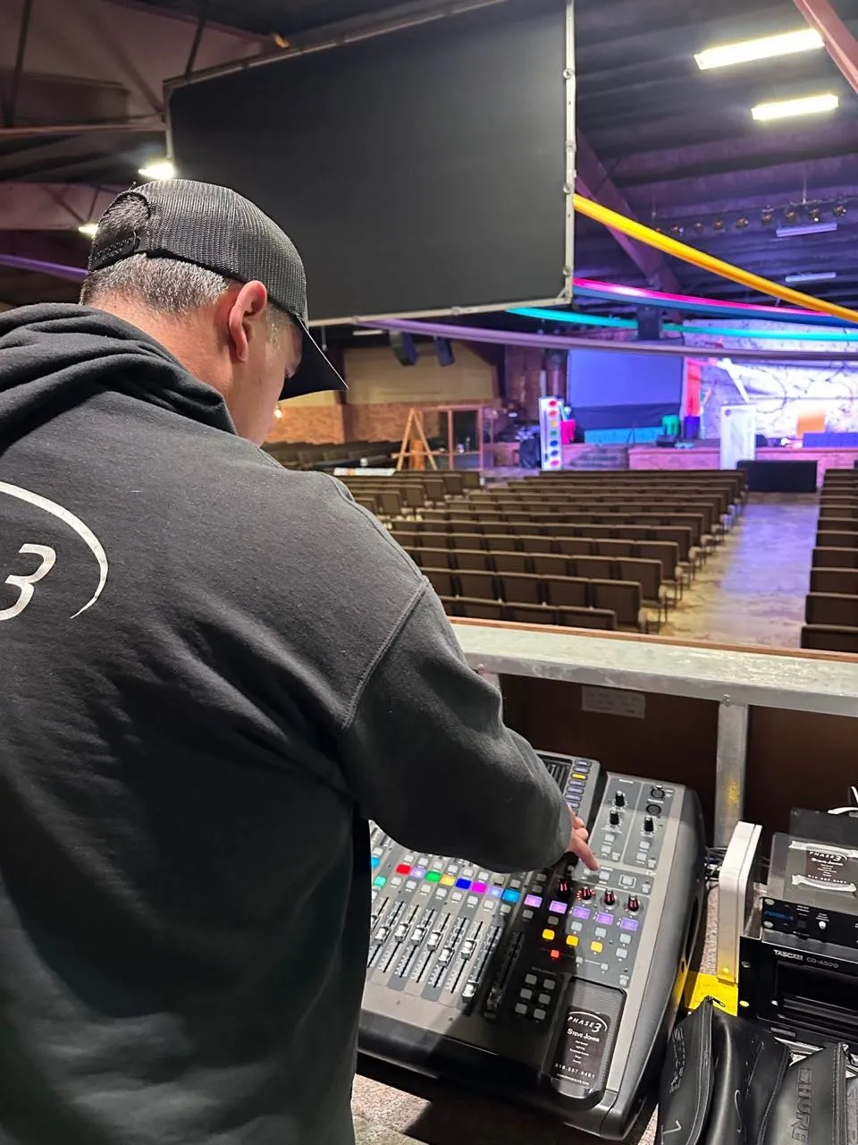 Phase 3 Live audio engineer at a mixing console overlooking an auditorium before an event