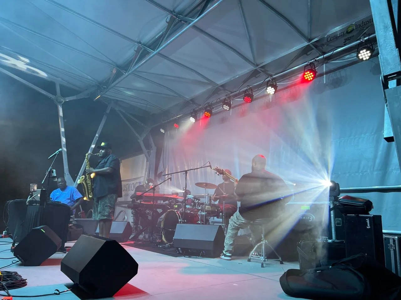 Band performing on an outdoor festival stage with lighting and sound production by Phase 3 Live