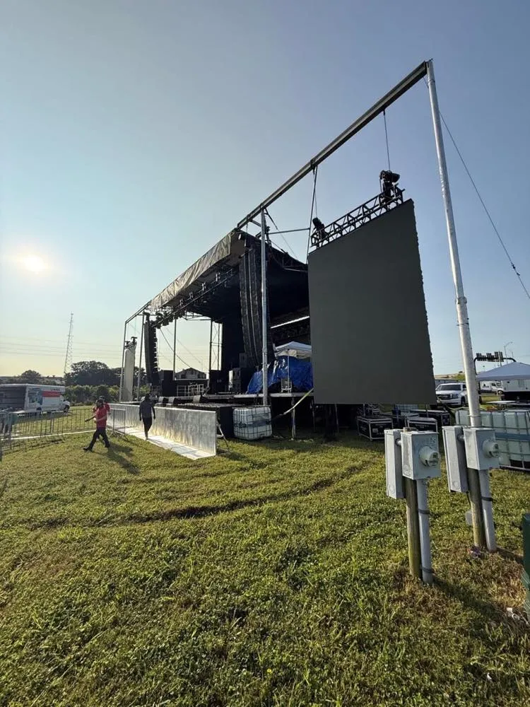 Golden-hour festival main stage with flown line arrays and projection screen built by Phase 3 Live