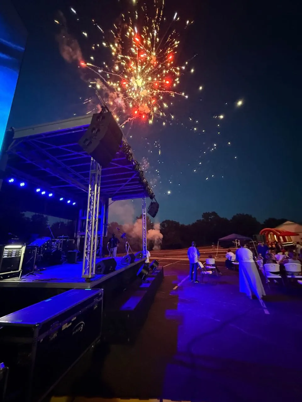 Fireworks exploding over an outdoor mobile stage with blue lighting at an evening event produced by Phase 3 Live