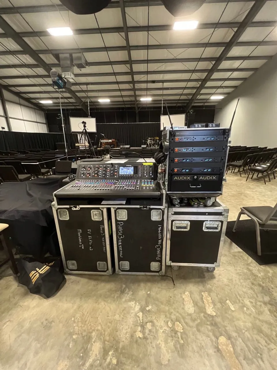 Front-of-house mixing console and wireless microphone rack on Phase 3 Live road cases at an indoor event