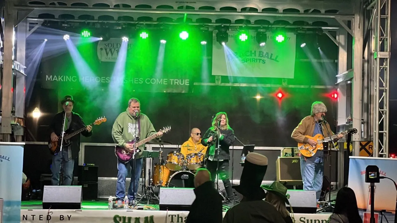 Band performing in green stage lighting with haze beams on a Phase 3 Live mobile stage
