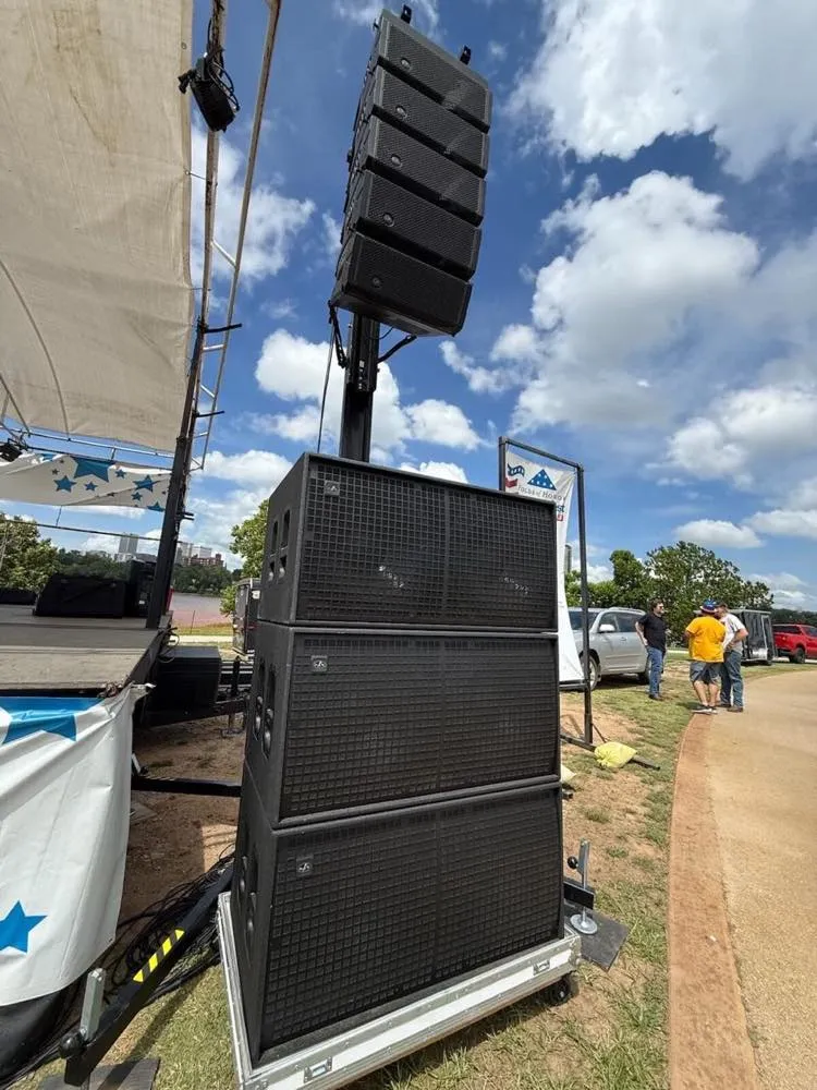 Ground-stacked line array and subwoofers at an outdoor festival stage supported by Phase 3 Live