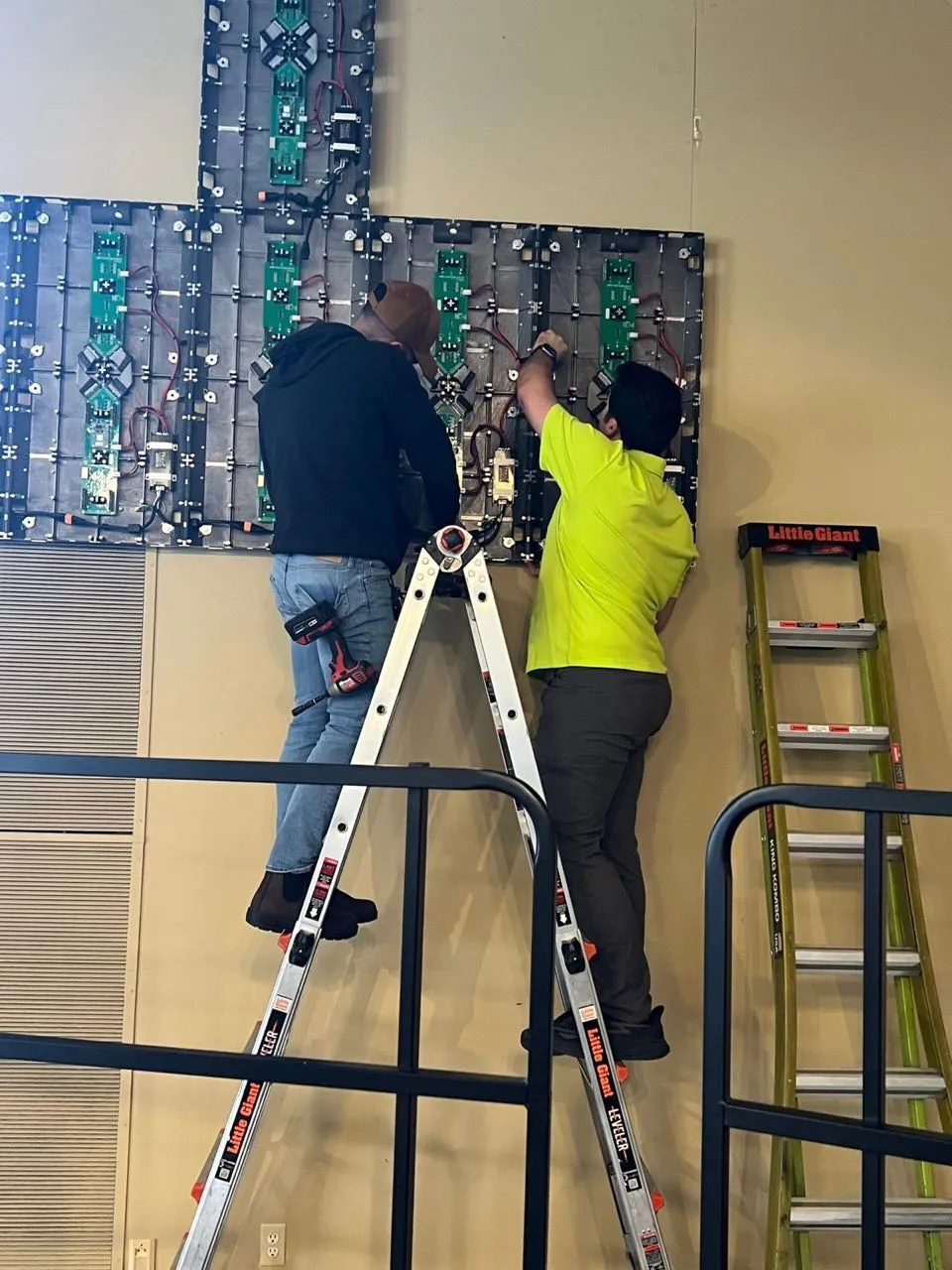 Phase 3 Live technicians on ladders wiring LED video wall panels during an indoor installation