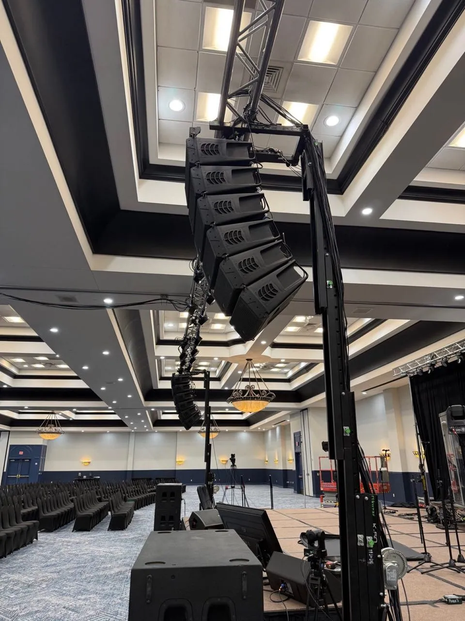 Flown line array on a ground-support tower rigged by Phase 3 Live in an ornate hotel ballroom.