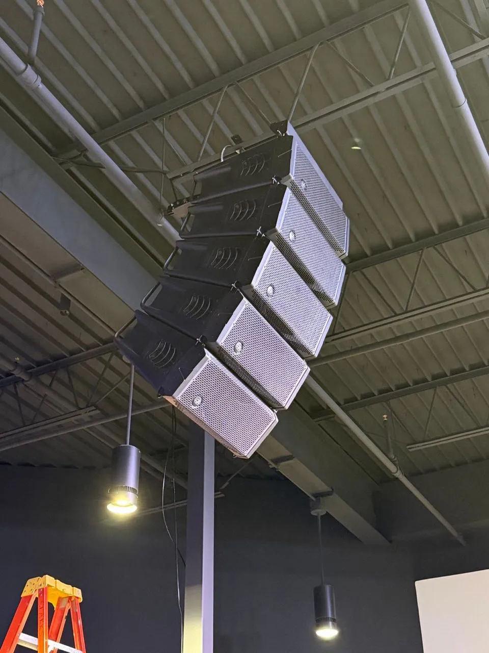 Line array speaker system installed overhead in a modern venue by Phase 3 Live