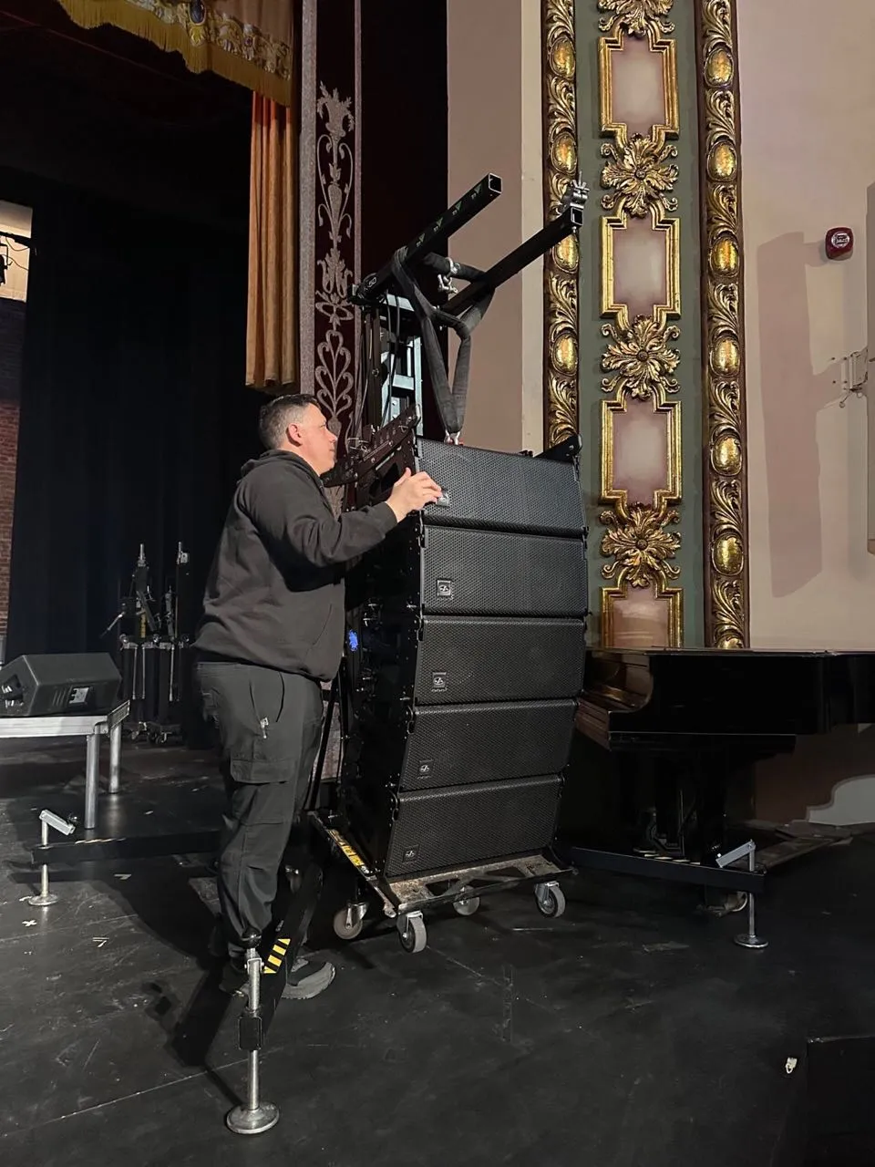 Phase 3 Live technician positioning a line array stack on stage in a historic gilded theater.