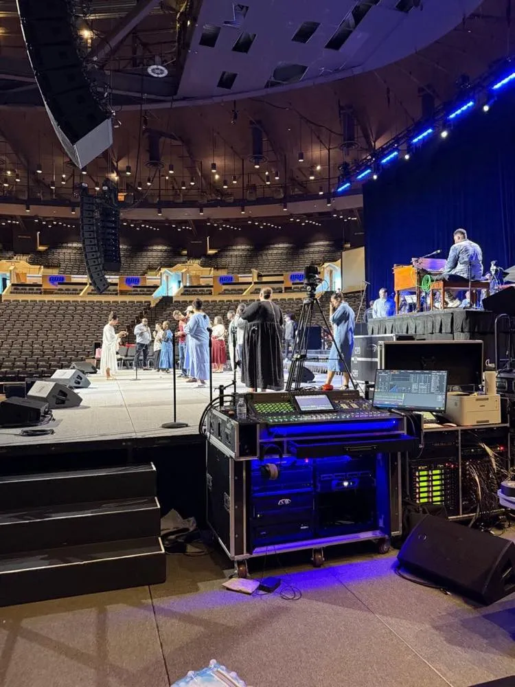 Monitor console and hung line array beside an arena stage during a conference supported by Phase 3 Live