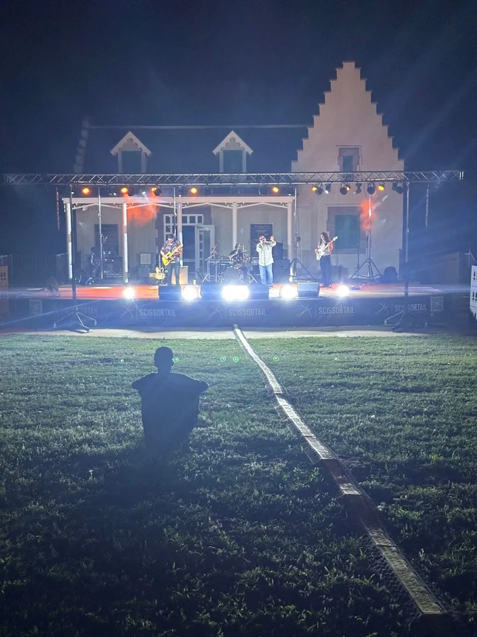 Night concert on a lit outdoor stage at a historic house venue produced by Phase 3 Live