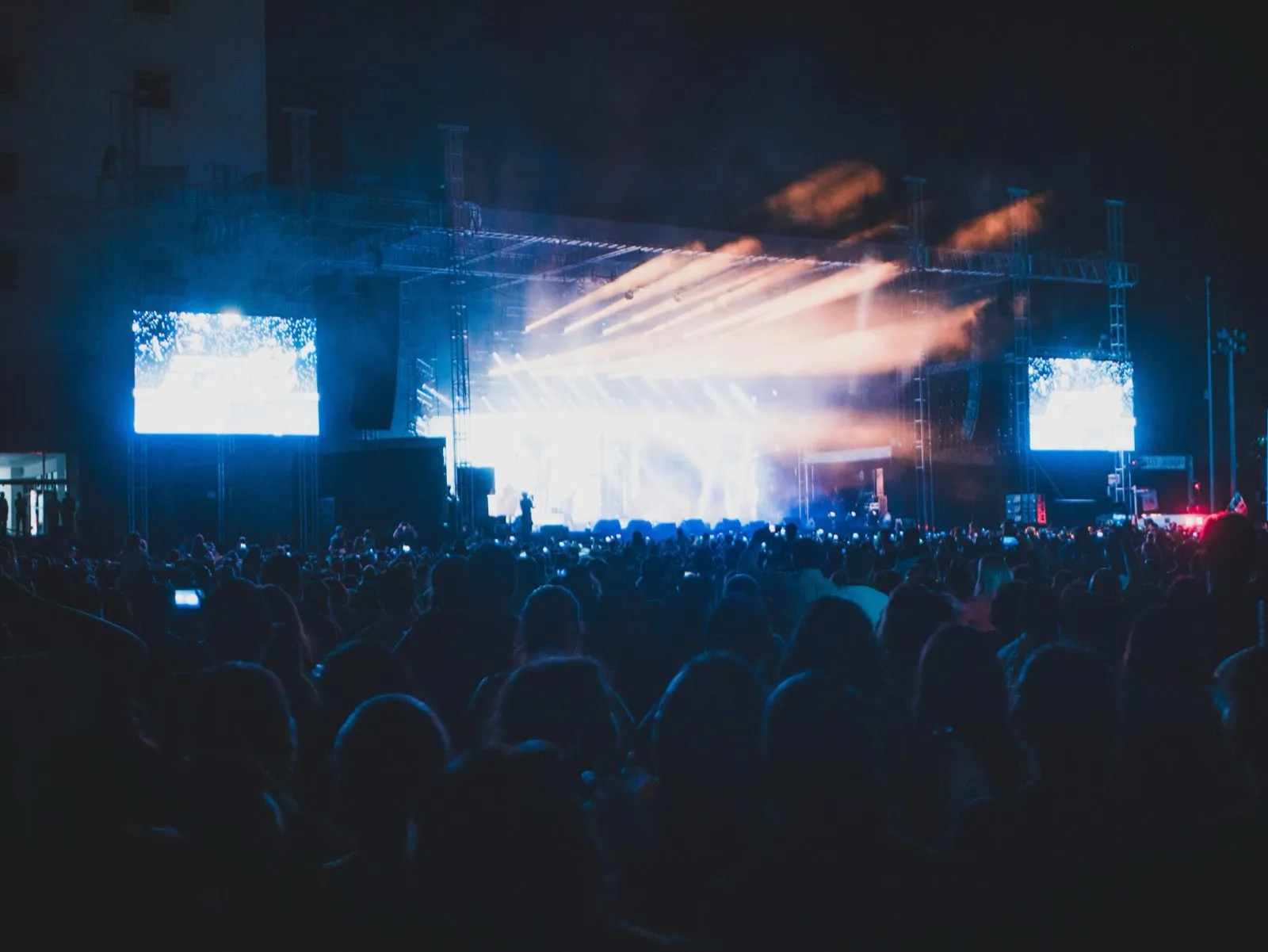 Night festival crowd facing a large concert stage with sweeping light beams and LED screens at a Phase 3 Live production