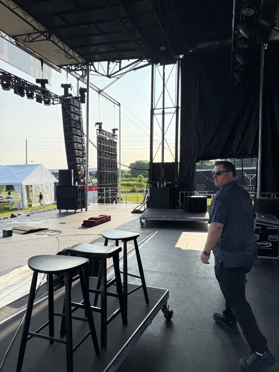 Phase 3 Live crew member on a large outdoor concert stage with flown line arrays and LED panels