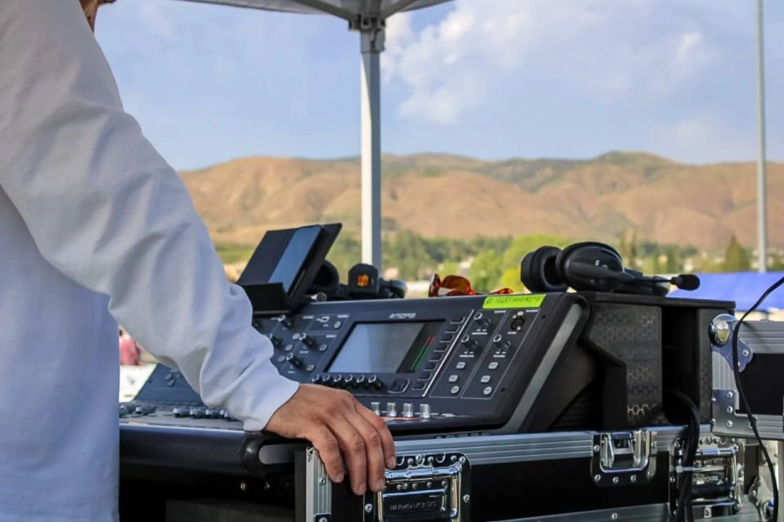 Phase 3 Live engineer at an outdoor digital mixing console with mountains in the background