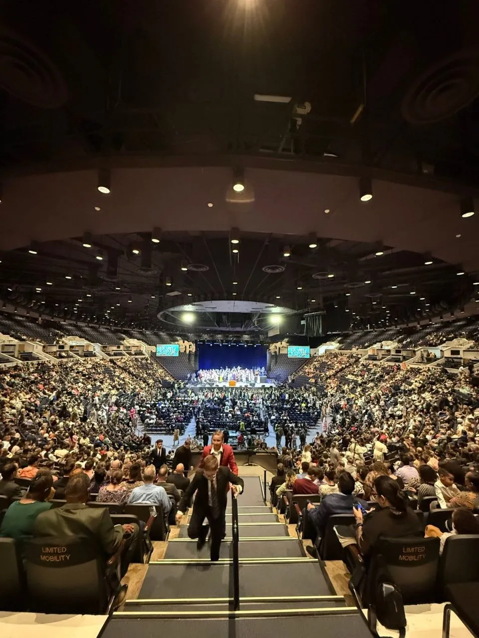 Packed arena during a large religious conference with staging and screens supported by Phase 3 Live