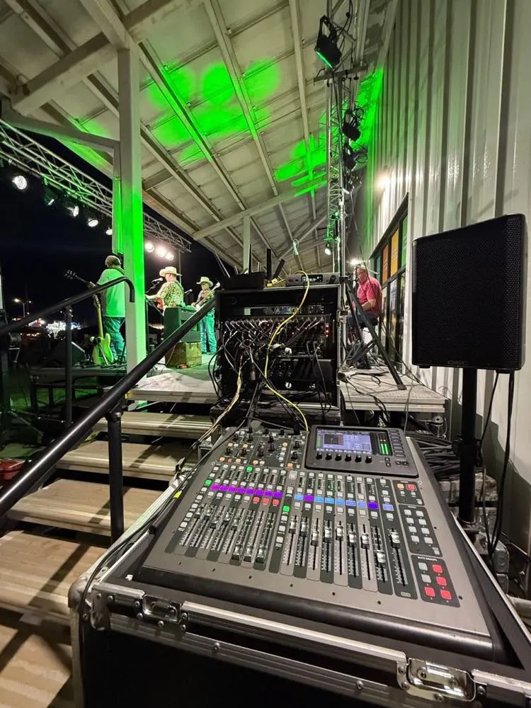 Front-of-house view of a country band on a pavilion stage with green lighting by Phase 3 Live