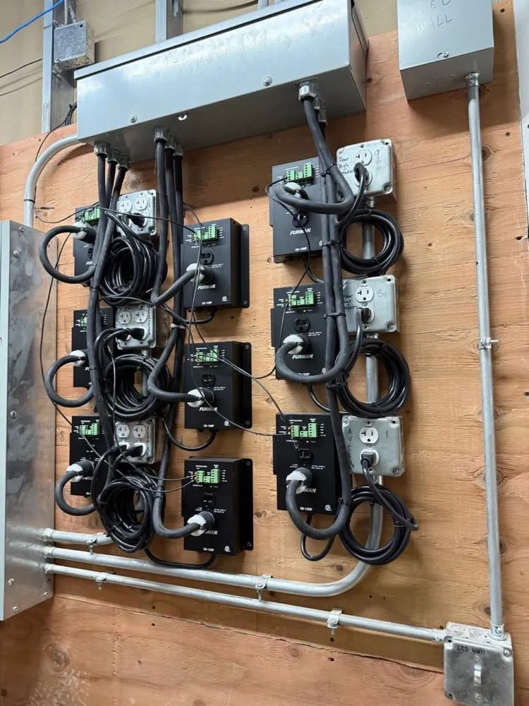 Power distribution wall with Furman conditioners and labeled circuits supporting an LED wall installation.