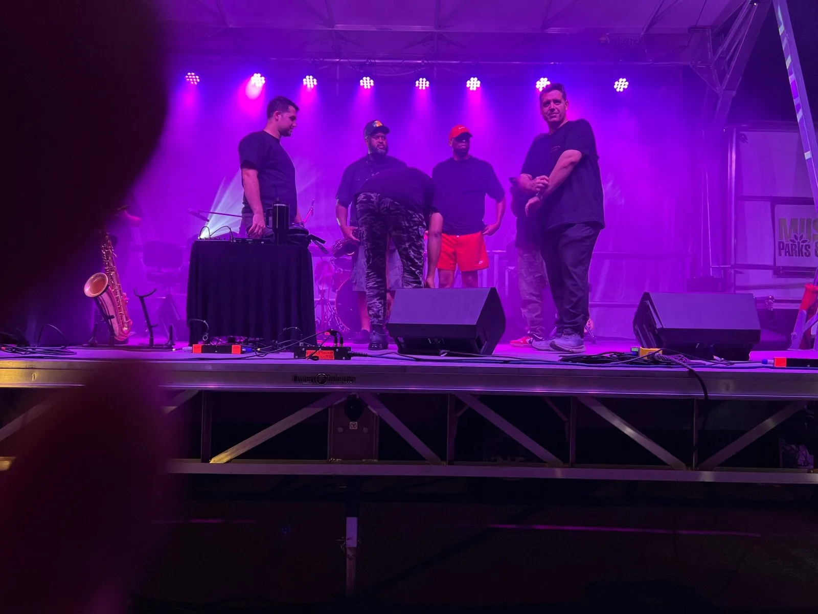 Crew on a purple-lit outdoor festival stage built and lit by Phase 3 Live