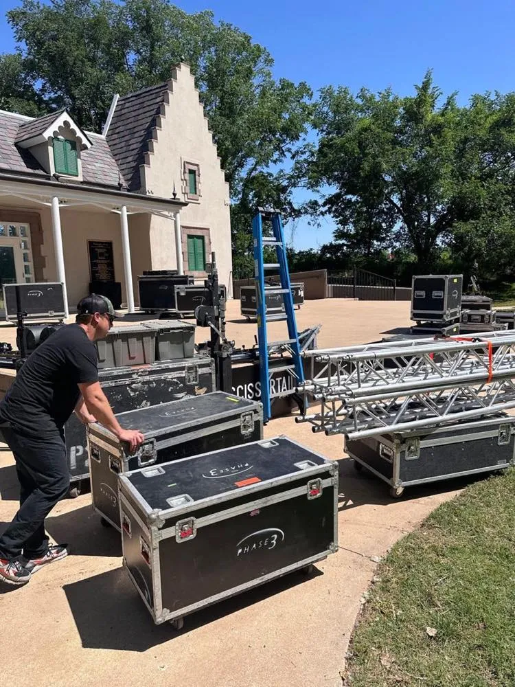 Phase 3 Live crew loading road cases and truss into a historic outdoor venue on a sunny day