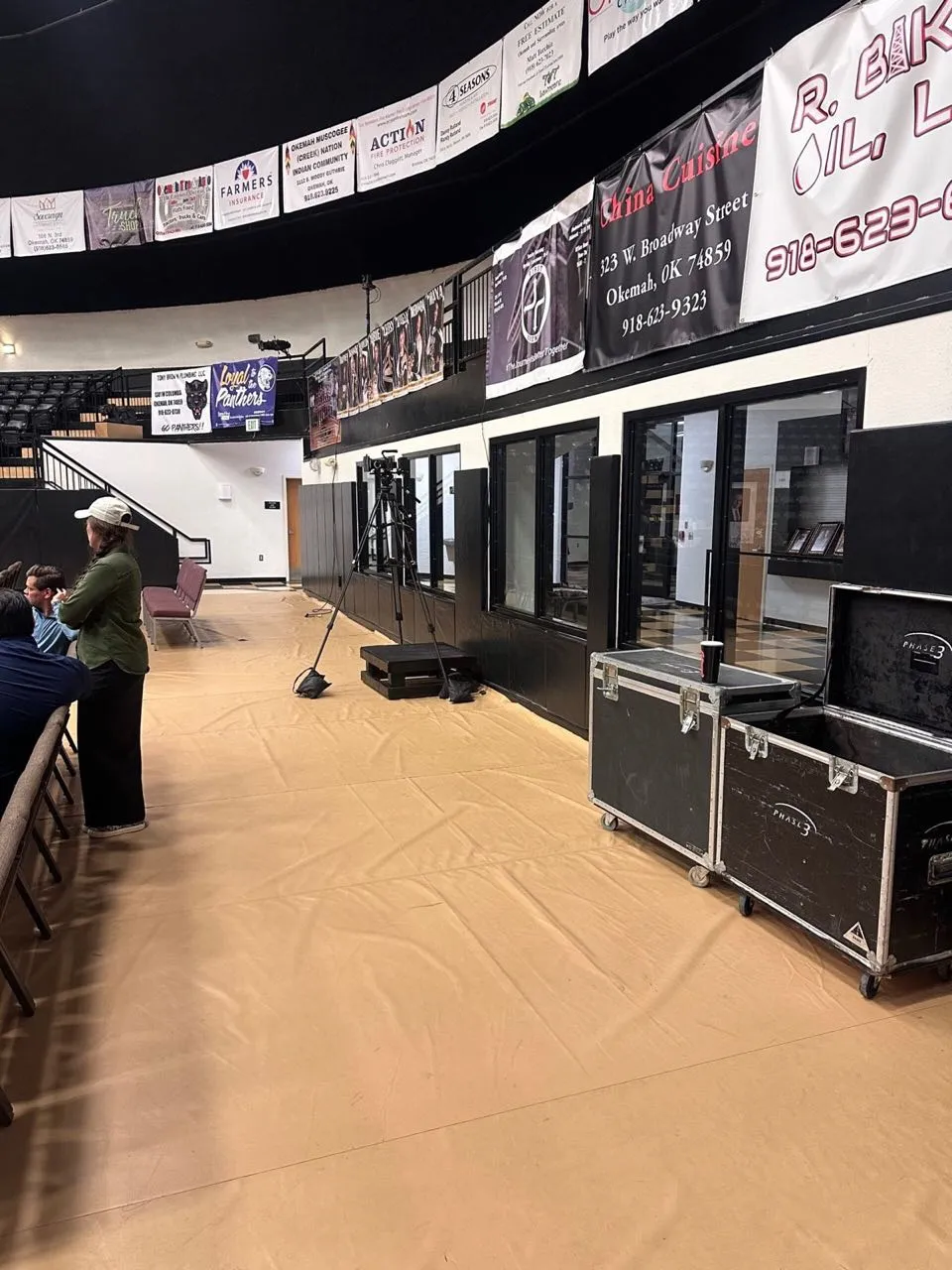 Phase 3 Live road cases and camera gear staged courtside during event setup in a school gymnasium